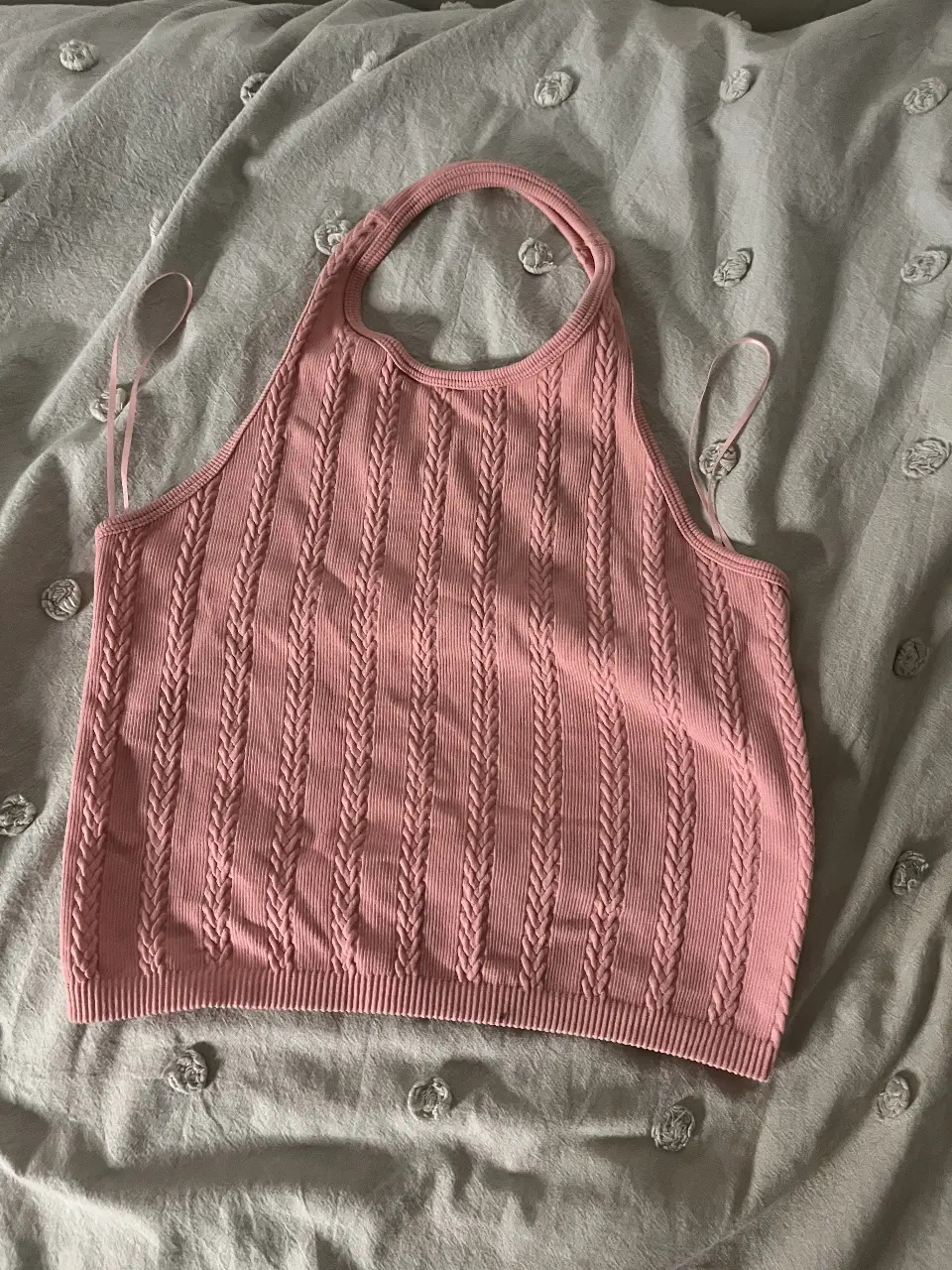 Top tejido de color rosa, con diseño de trenzas verticales y cuello halter. Ideal para un look casual y fresco.