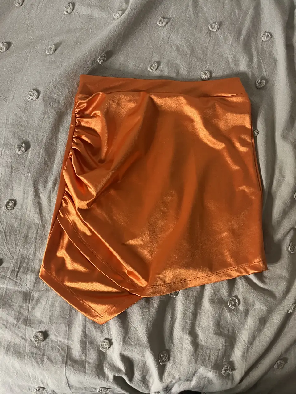 Pollera asimétrica naranja con fruncido en un lateral. Ideal para un look de fiesta o salida.