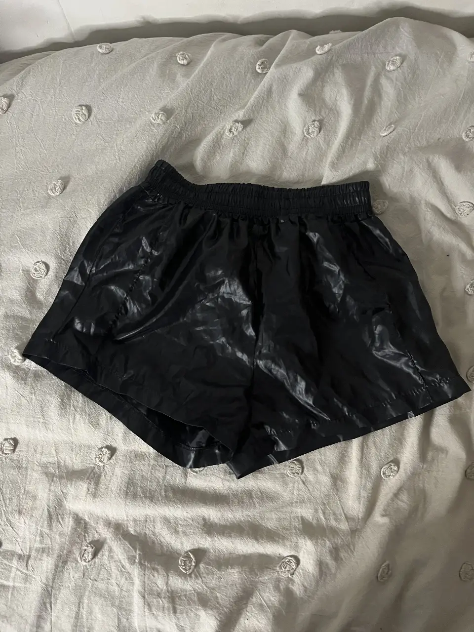 Short deportivo negro brillante, ideal para actividades físicas o un look casual y moderno. Confeccionado con un material que simula charol, ofrece un estilo único y llamativo. Perfecto para combinar con tops deportivos o remeras.