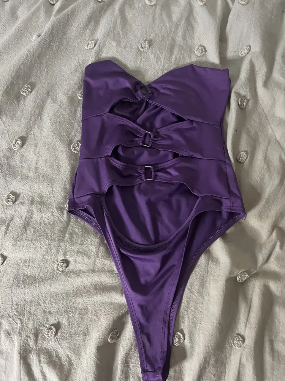 Body enterizo violeta con aberturas y detalles de hebillas. Ideal para lucir en la playa o pileta.
