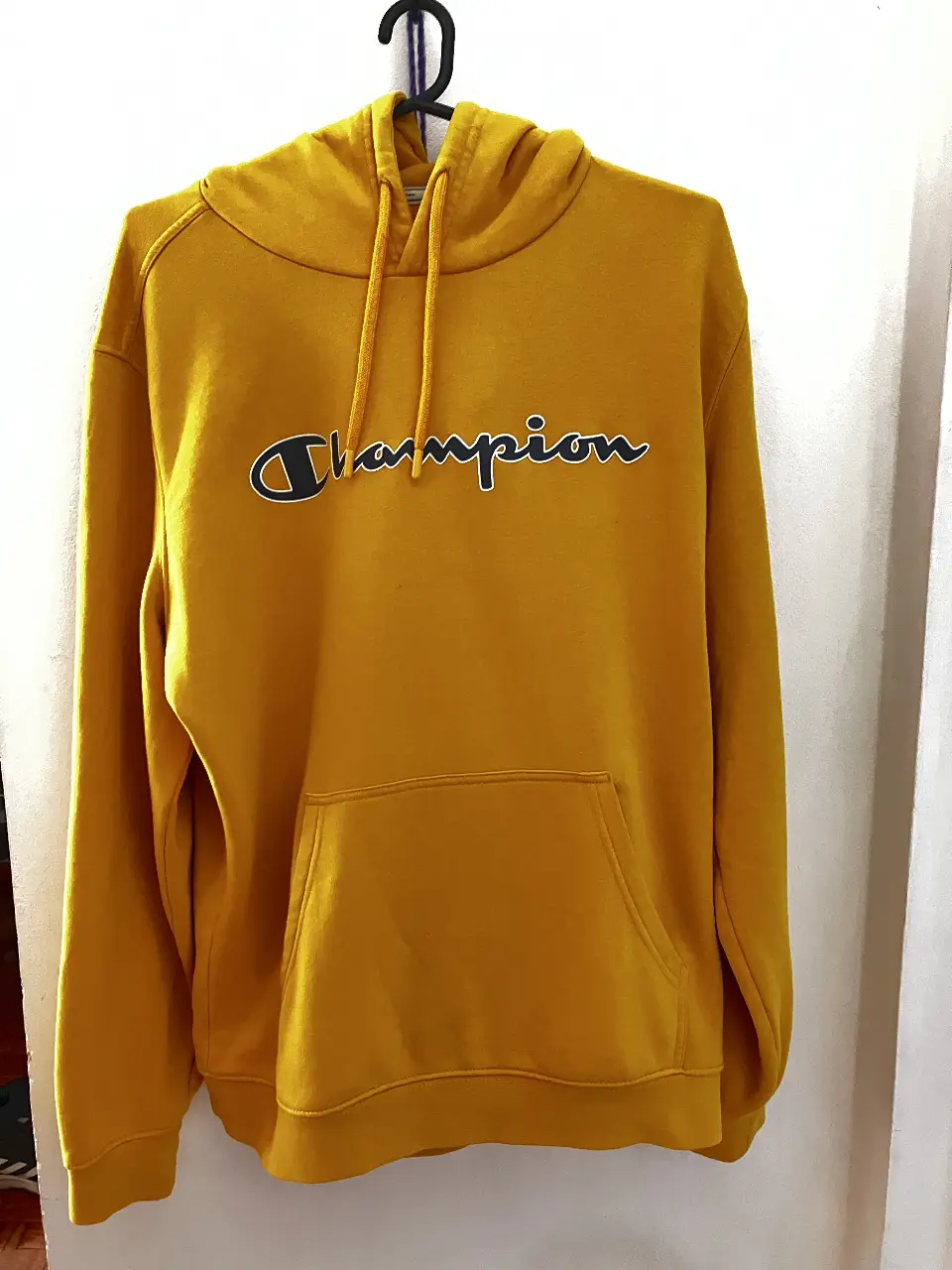 Buzo canguro Champion amarillo, con capucha y bolsillo frontal. Ideal para un look casual y cómodo.