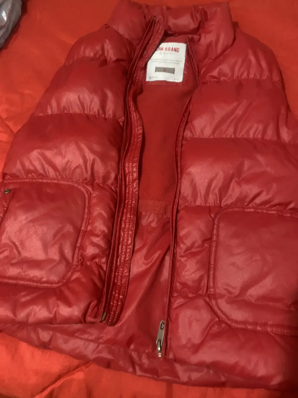 Chaleco rojo acolchado de la marca CHK-BRAND, ideal para el invierno. Cuenta con cierre y bolsillos.