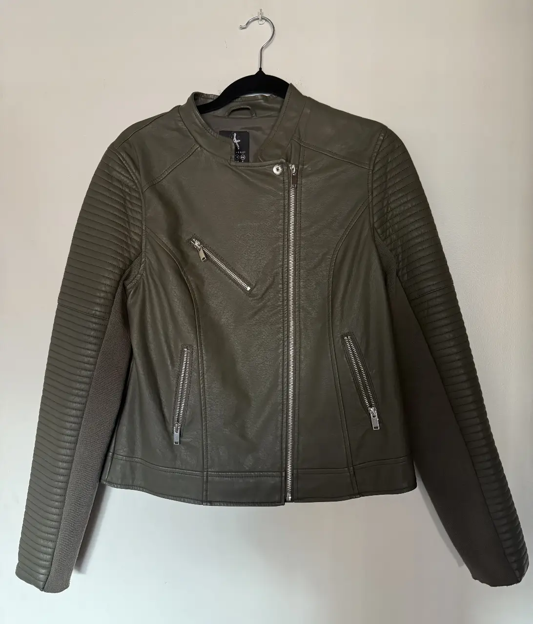 Chaqueta de cuero sintético verde militar para mujer. Diseño biker con cierre asimétrico, detalles acolchados en hombros y mangas. Talle 12 (40/8/44). Ideal para un look moderno y canchero.