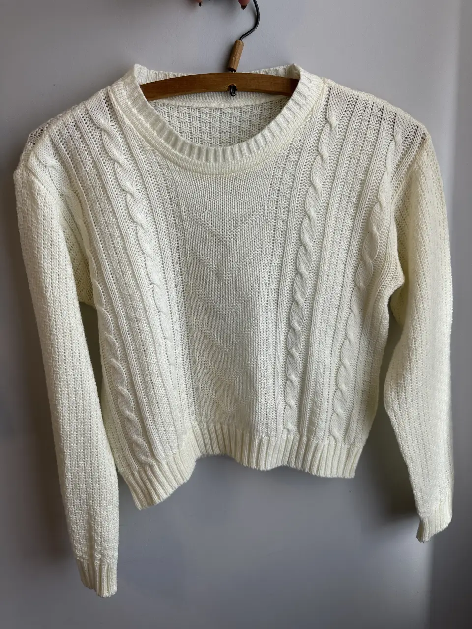 Sweater tejido de color blanco, con diseño de trenzas y detalles acanalados. Ideal para un look casual y abrigado.
