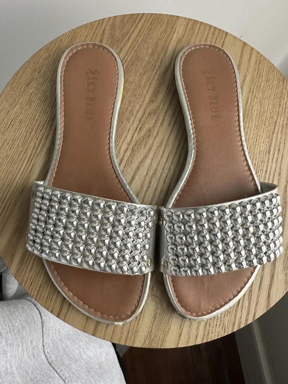 Sandalias de mujer plateadas con detalles de tachas. Ideales para un look casual y moderno. Suela marrón.
