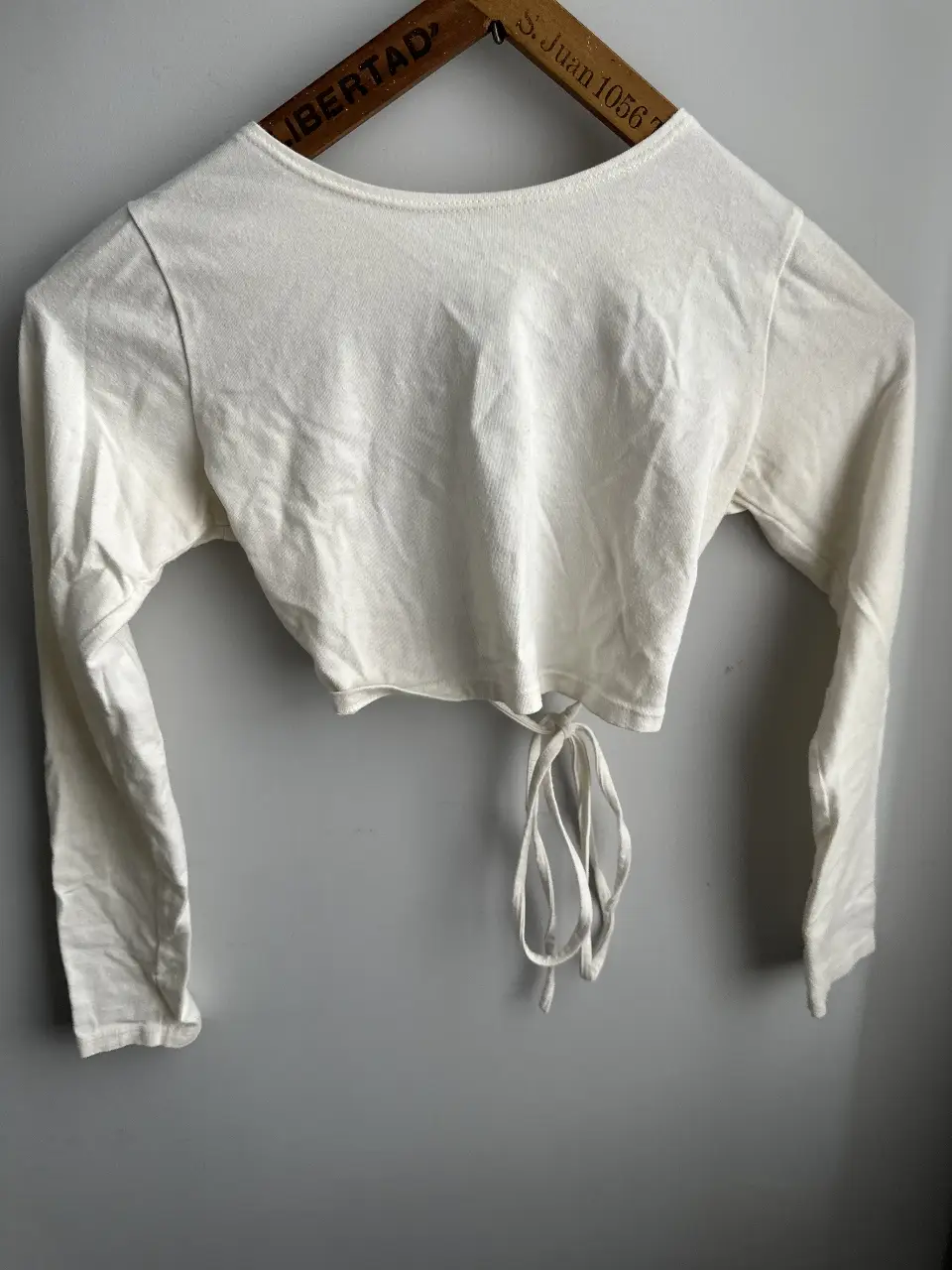 Top blanco manga larga con espalda descubierta y lazo. Ideal para un look moderno y versátil.