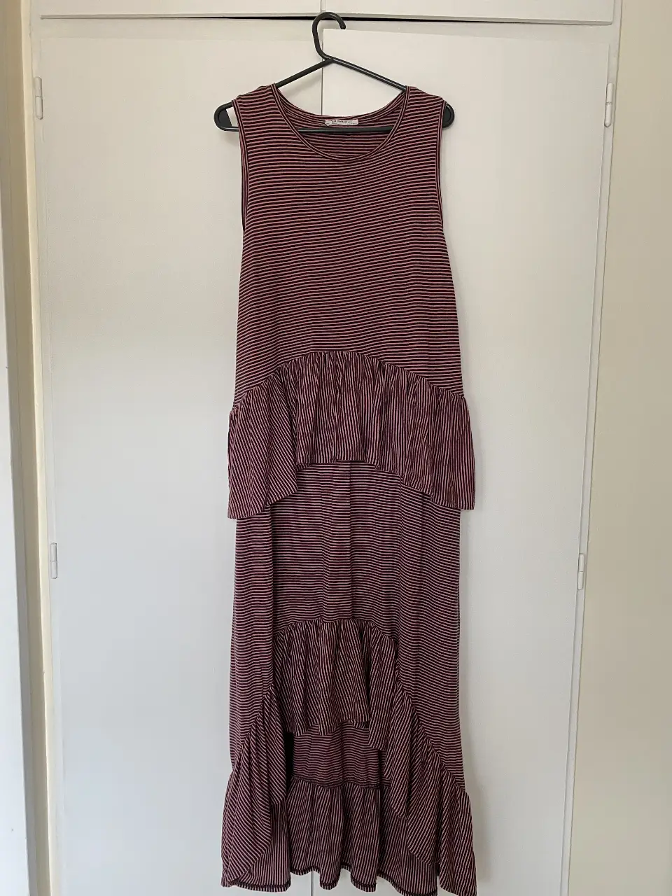 Vestido midi a rayas rojas y negras, con volados en la falda y corte en la cintura. Ideal para un look casual y fresco.