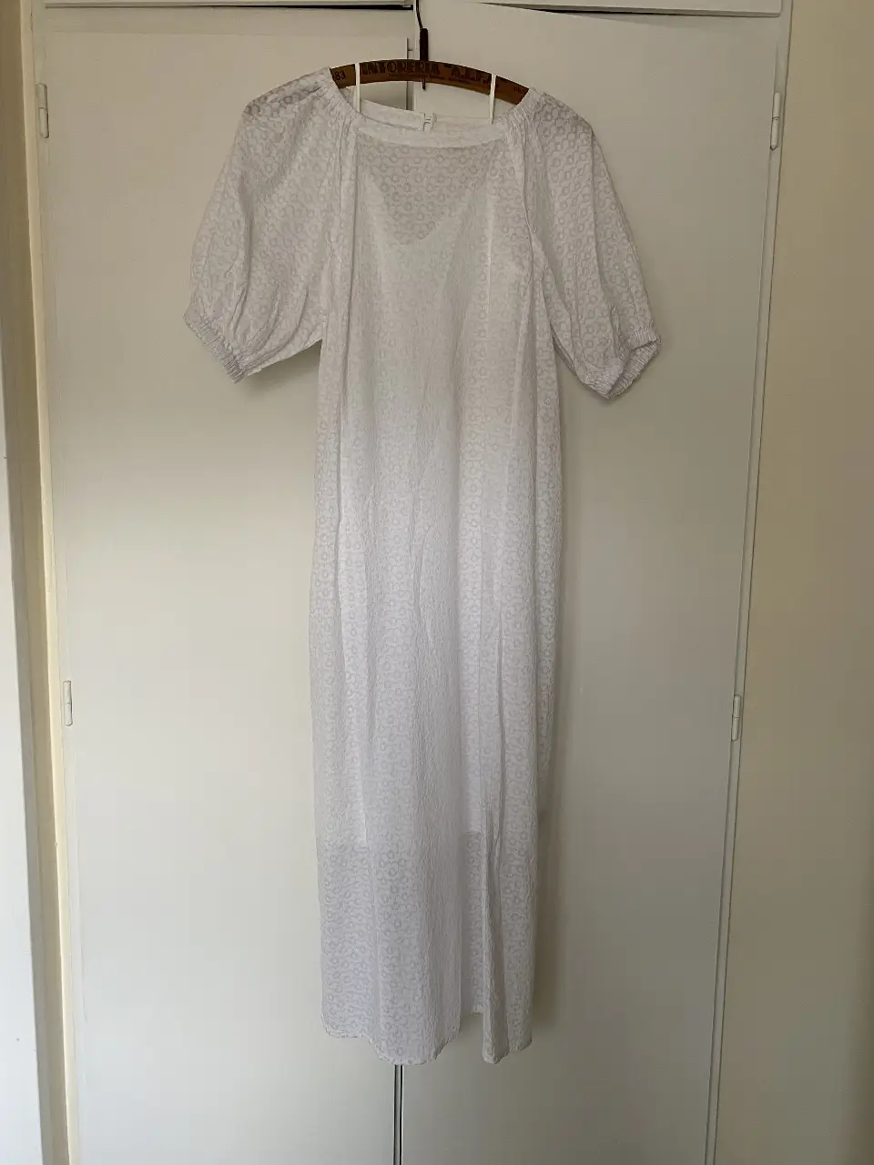 Vestido midi blanco de tela liviana con mangas cortas abullonadas y detalle de estampado sutil. Ideal para un look fresco y cómodo.