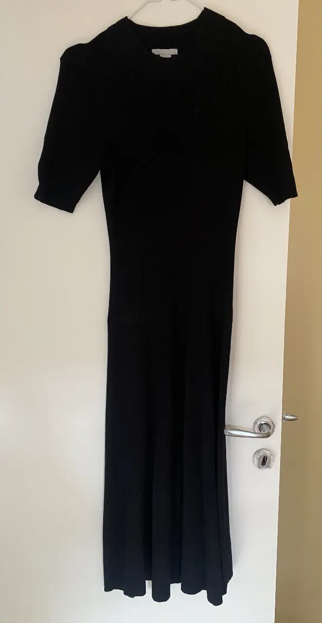 Vestido midi negro de punto, tipo morley pero se abre a partir de la cadera, ideal para un look elegante y versátil. Perfecto para combinar con diferentes accesorios y crear outfits para diversas ocasiones.