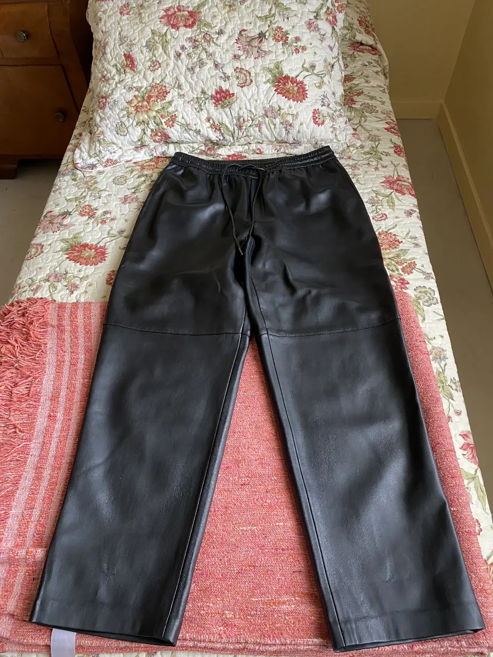 Pantalón de cuero sintético negro, con cintura elastizada y cordón para ajustar. Ideal para un look moderno y versátil.