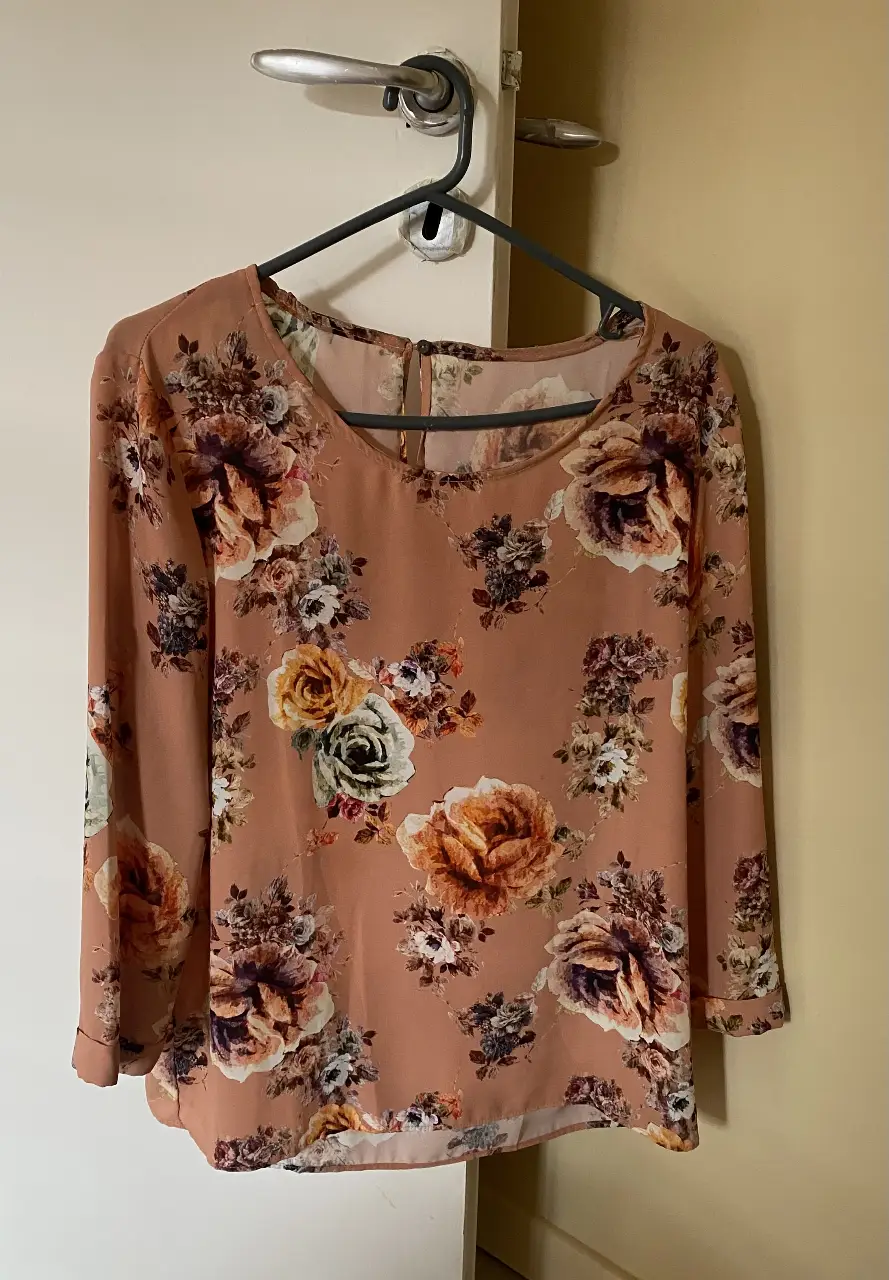 Blusa de mujer con estampado floral en tonos rosados y detalles en la manga. Ideal para un look elegante y femenino.