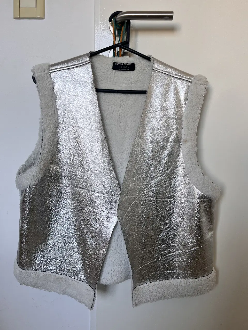 Chaleco de mujer plateado con interior de piel sintética blanca. Ideal para un look moderno y abrigado. Perfecto para usar en ocasiones especiales o para darle un toque de estilo a tu outfit diario.