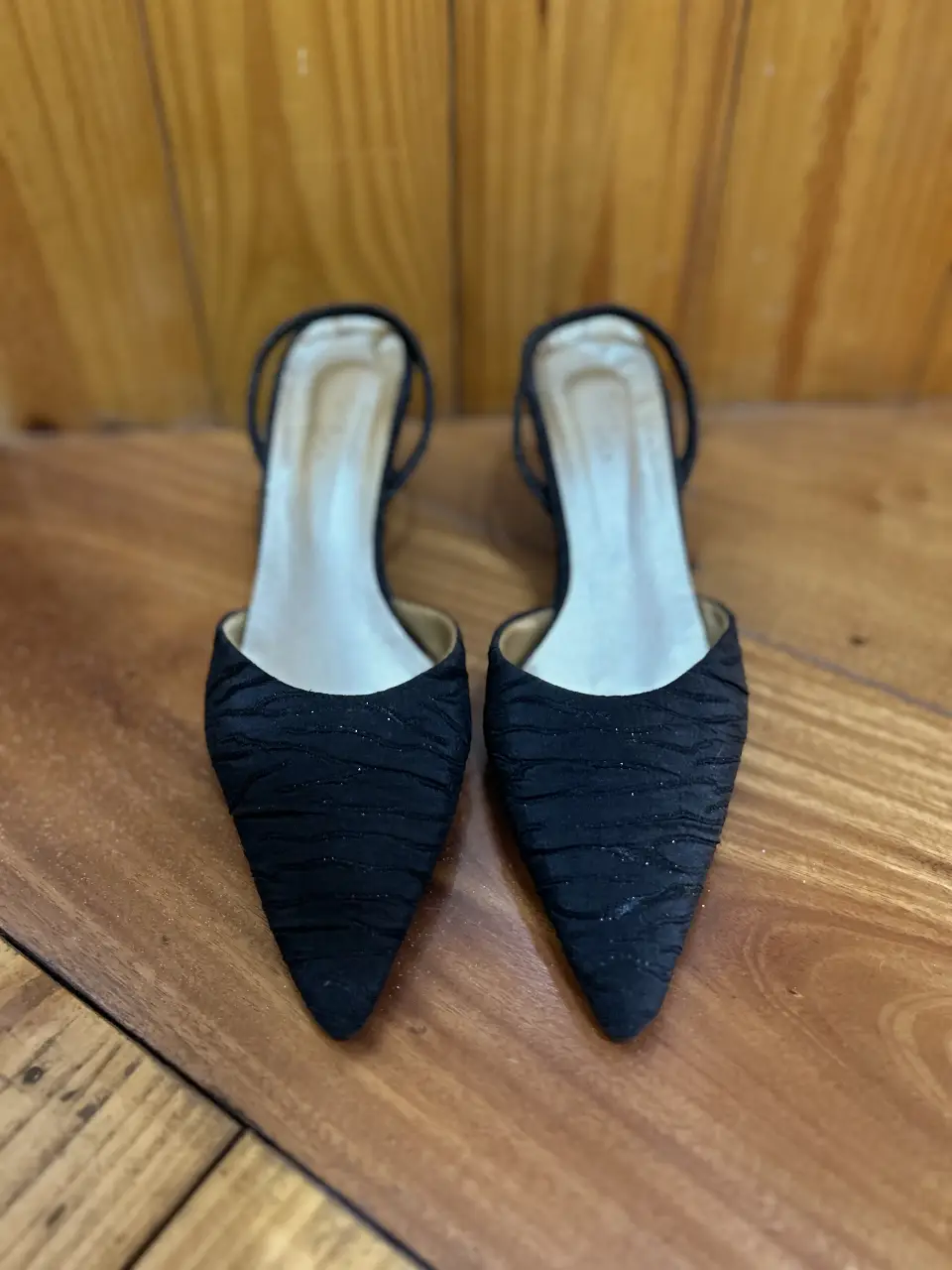 Elegantes zapatos de taco alto negros, con diseño de punta fina y detalle fruncido en la capellada. Ideales para eventos formales y fiestas.