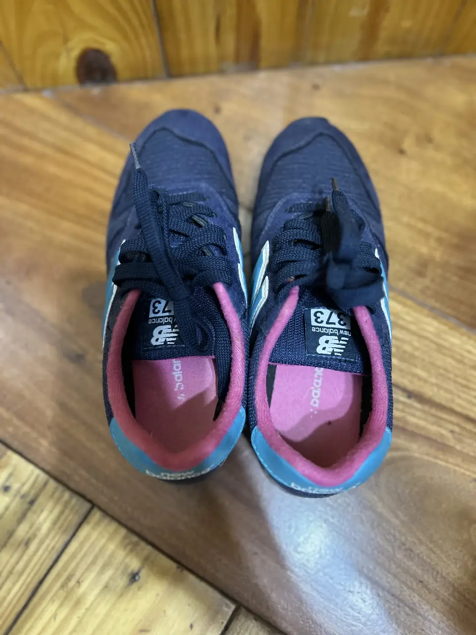 Zapatillas New Balance 373 para mujer, color azul marino con detalles en rosa y celeste. Ideales para uso diario y actividades deportivas.