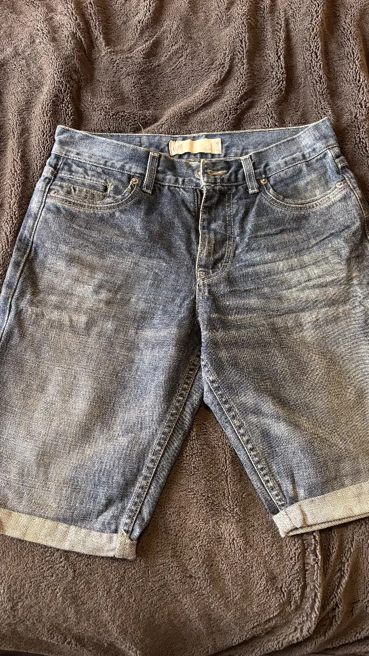 Short de jean azul de hombre, con dobladillo en el borde. Talle 30. Ideal para un look casual y cómodo.