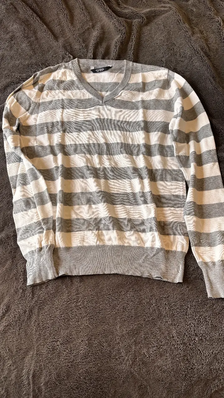 Sweater de hombre a rayas grises y blancas, con cuello en V. Ideal para un look casual y cómodo.