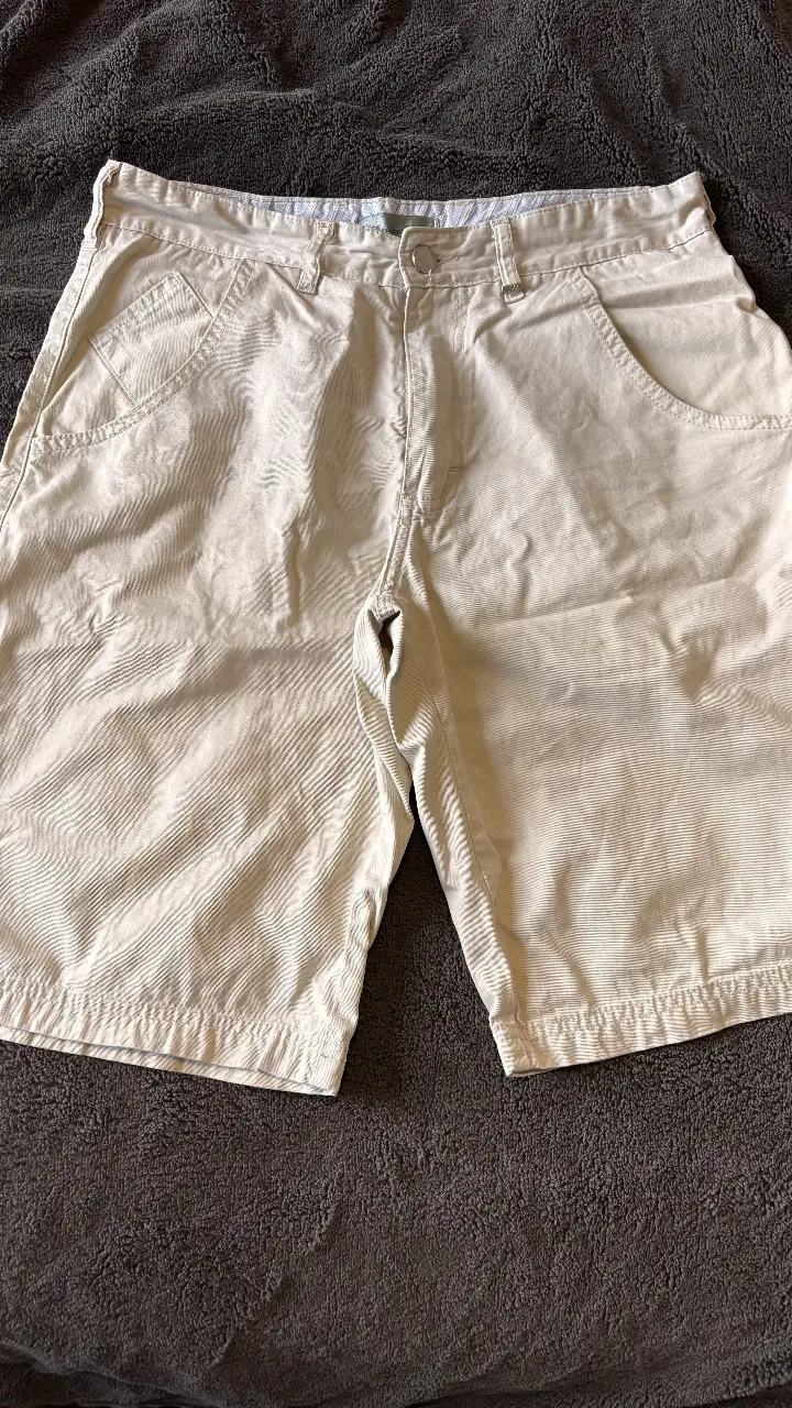 Short de hombre color crudo de la marca Christian Dior. Confeccionado en corderoy, presenta un diseño clásico con bolsillos delanteros y traseros. Ideal para un look casual y cómodo.