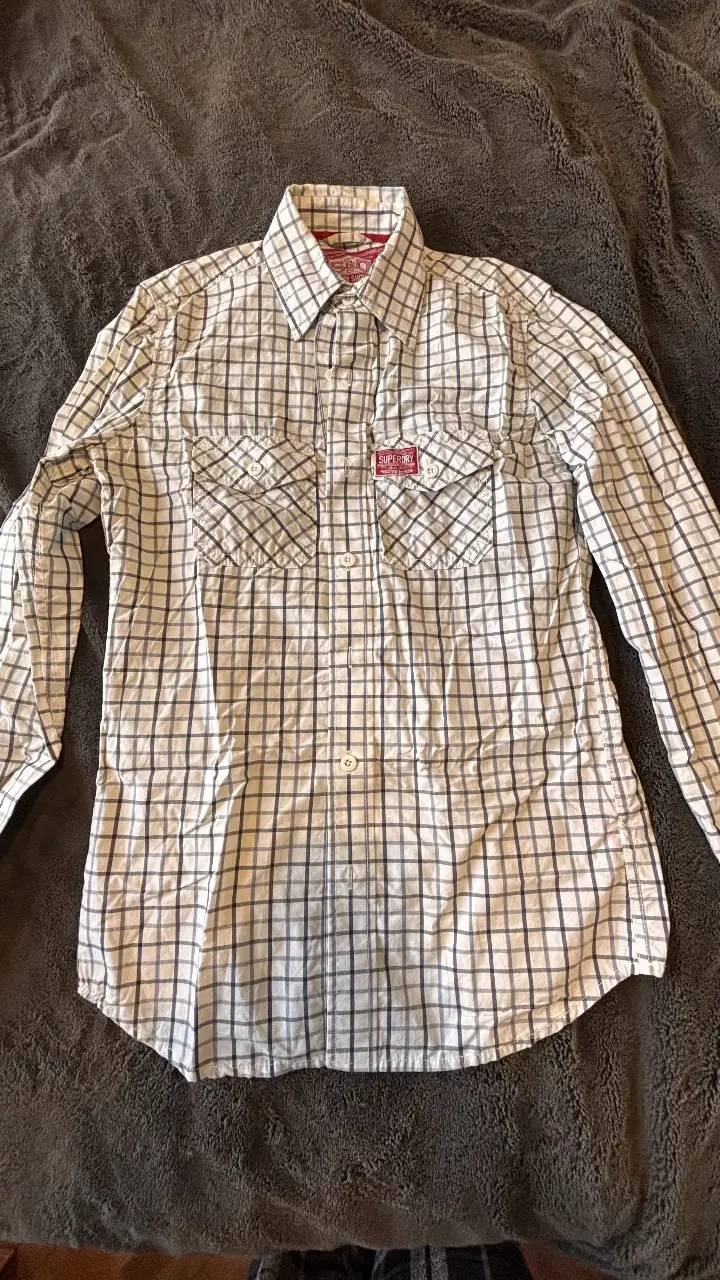 Camisa a cuadros Superdry para hombre, manga larga, con dos bolsillos delanteros y detalles de la marca. Ideal para un look casual y moderno.