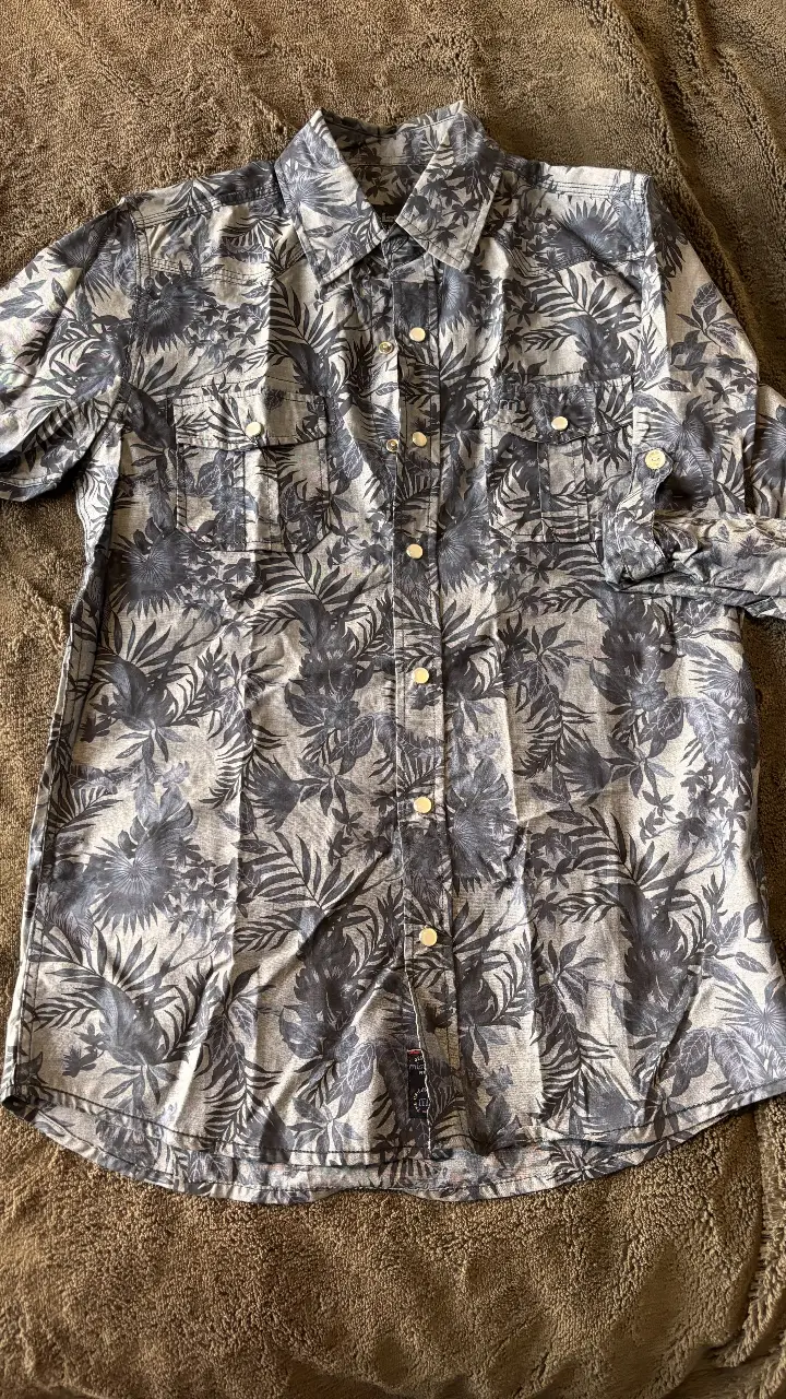 Camisa de hombre con estampado floral en tonos grises y blancos. Manga larga, con dos bolsillos delanteros y botones. Ideal para un look casual y moderno.