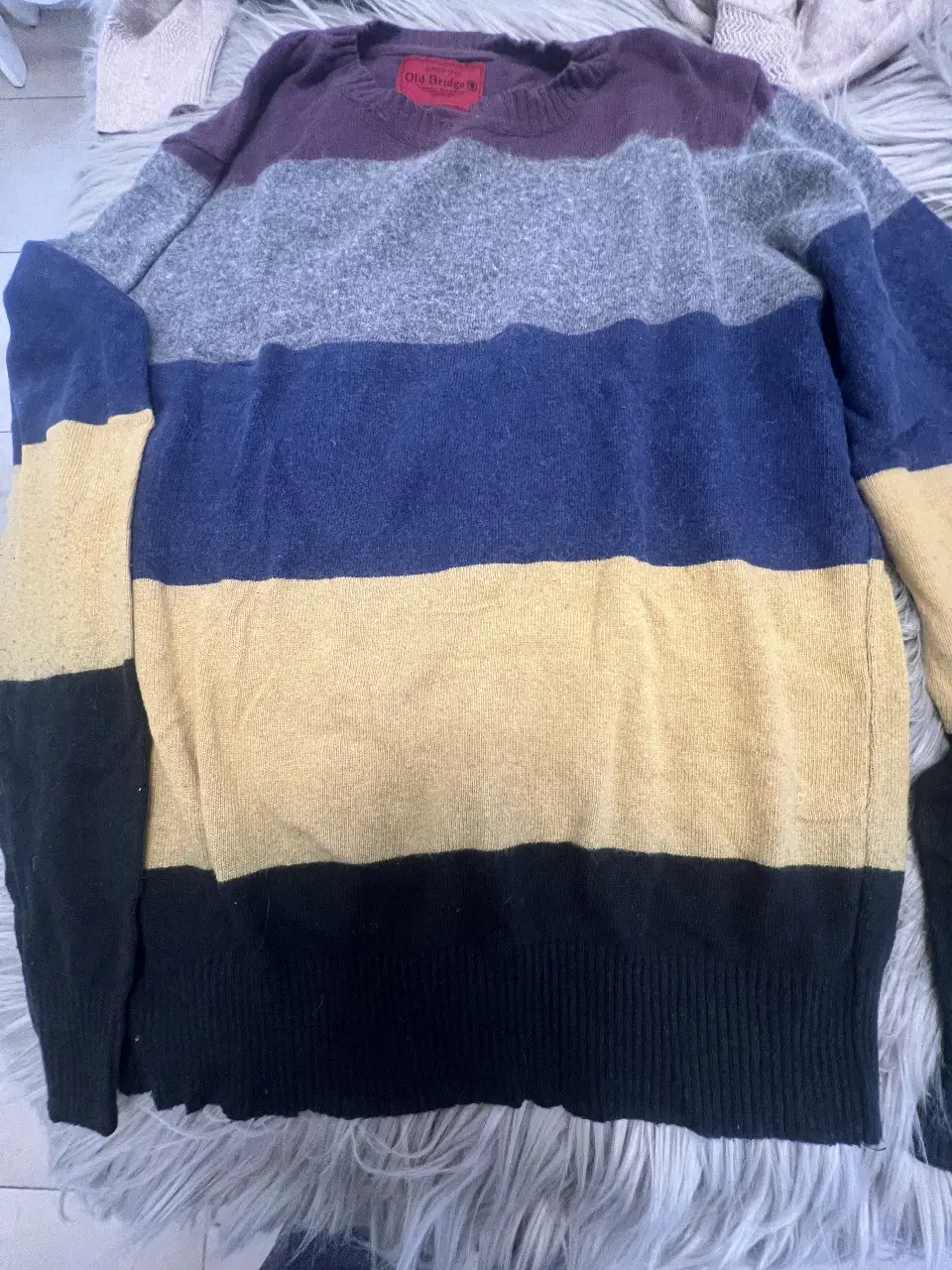 Sweater de hombre Old Bridge a rayas horizontales. Confeccionado en una combinación de colores vibrantes: violeta, gris, azul, amarillo y negro. Ideal para un look casual y abrigado.