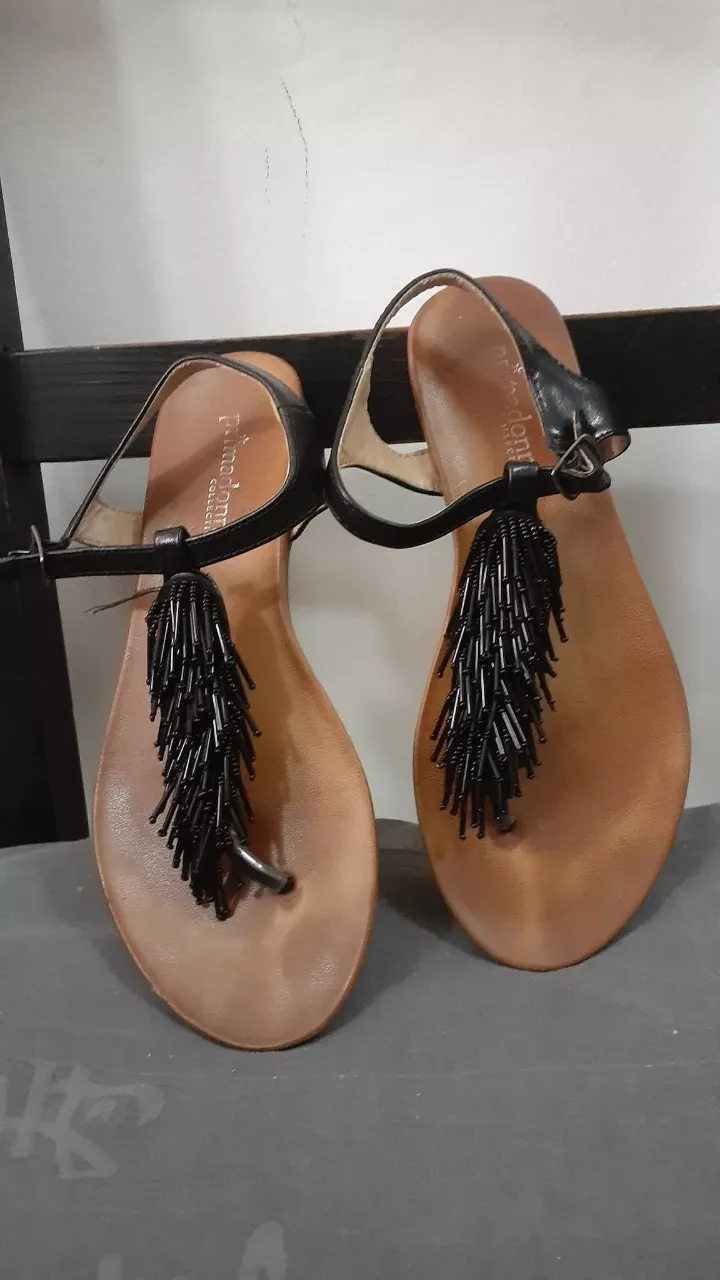 Sandalias chatitas negras con tiras finas y detalle de flecos con mostacillas. Ideales para un look boho chic o playero.