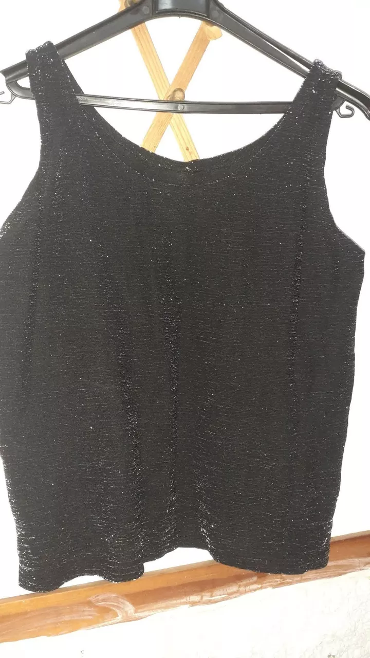 Top negro brillante, ideal para eventos o salidas nocturnas. Su diseño sin mangas y con un toque de brillo lo hace perfecto para destacar.