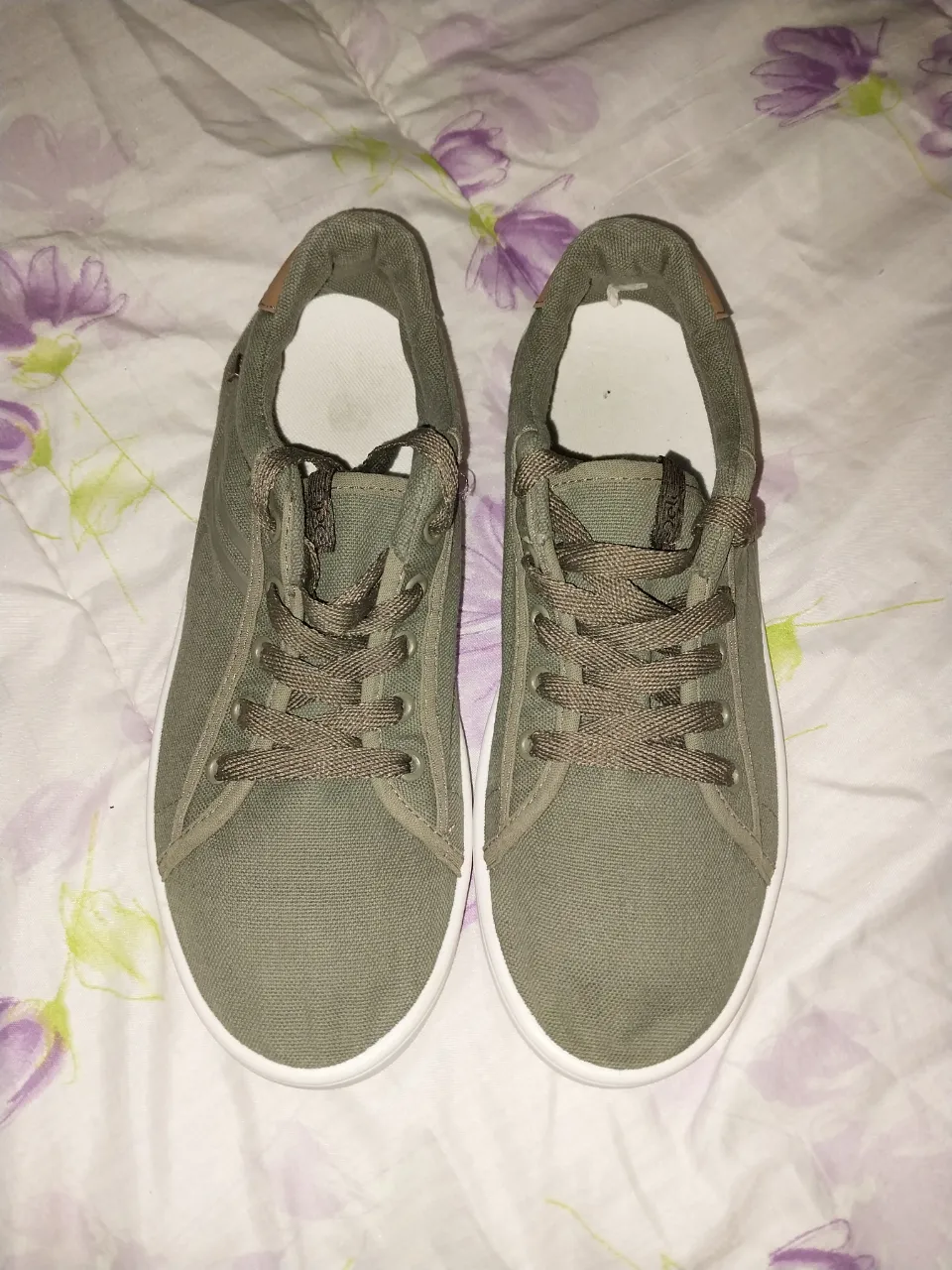 Zapatillas de lona color verde militar, con cordones y suela blanca. Ideales para un look casual y cómodo.