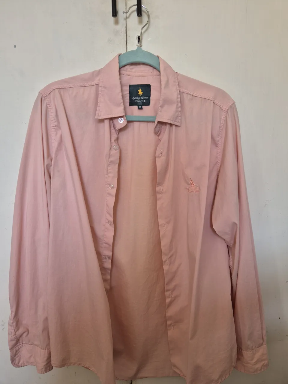 Camisa de hombre color rosa, manga larga, con logo bordado en el pecho. Ideal para un look casual y moderno. talle M