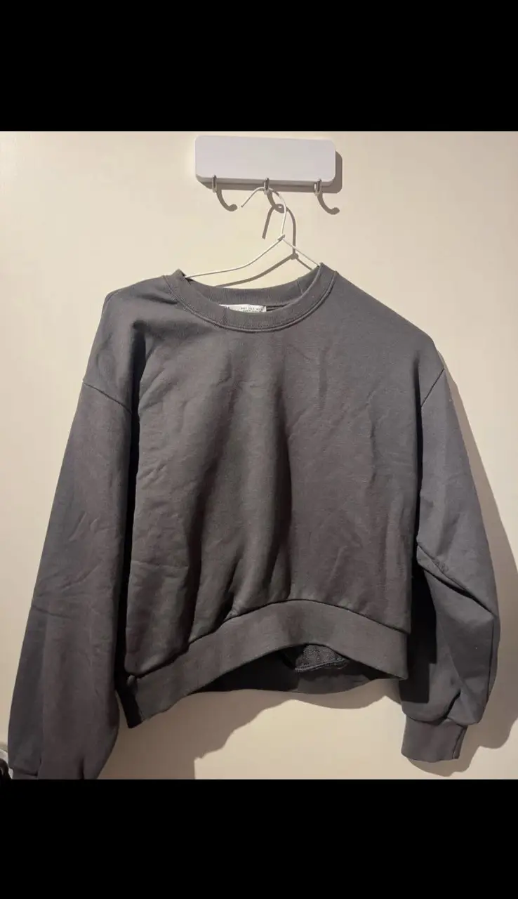 Buzo de cuello redondo gris oscuro de la marca Zara, ideal para un look casual y cómodo. 