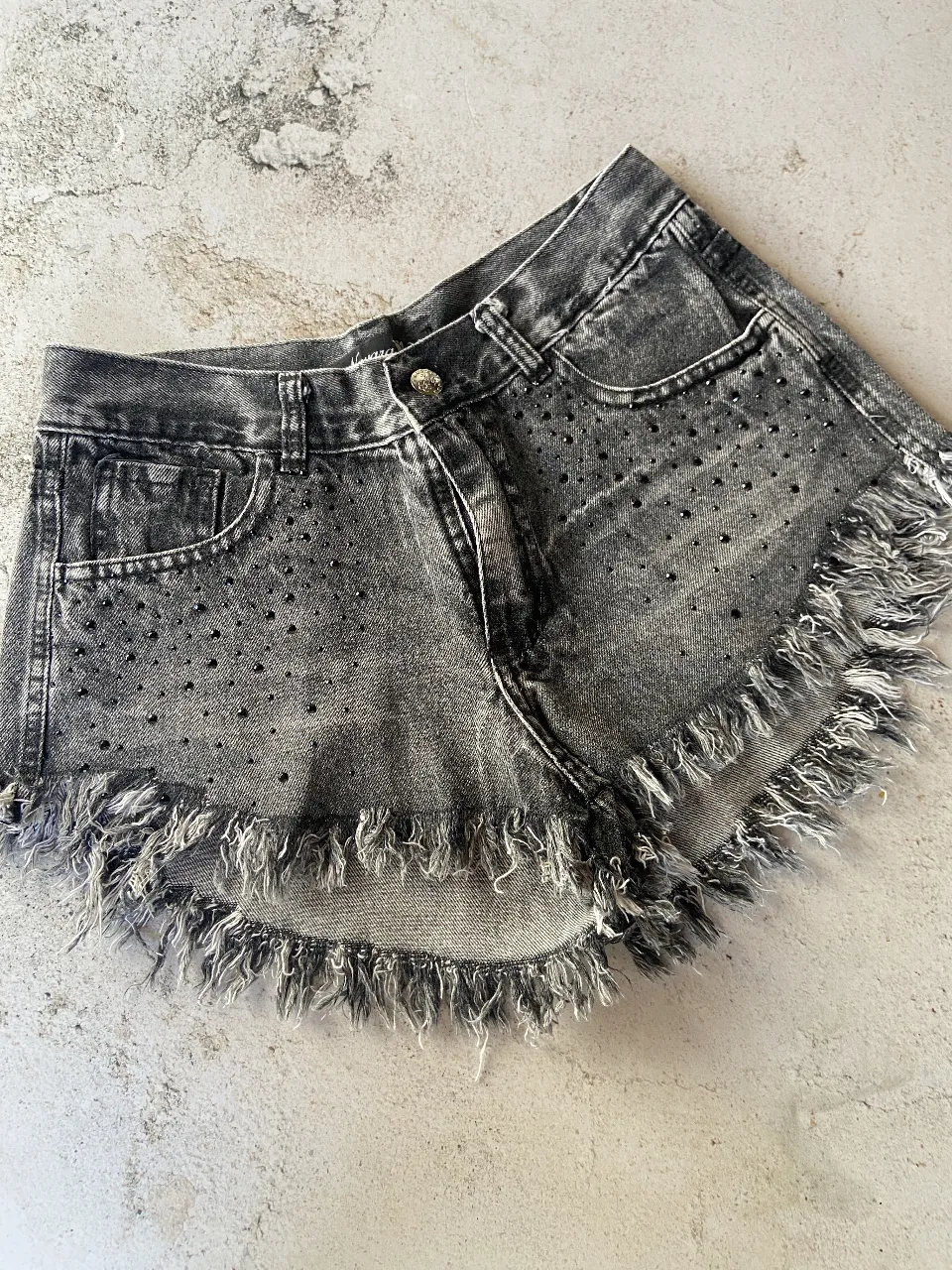 DISPONIBLE EN 38 y 40
Shorts de jean grises con roturas y flecos en el bajo. Tienen tachitas negras incrustadas en toda la parte delantera y trasera. Ideales para un look canchero y moderno.