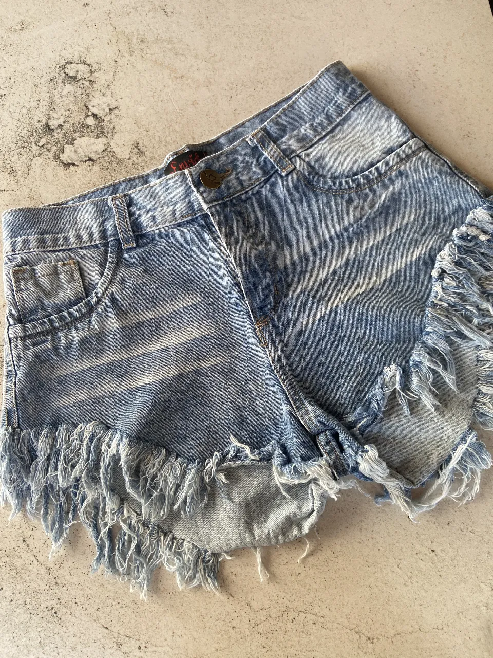 DISPONIBLE EN 38, 40 y 44
Shorts de jean tiro alto con roturas y flecos en los bordes. Un clásico para el verano, ideales para un look casual y descontracturado.