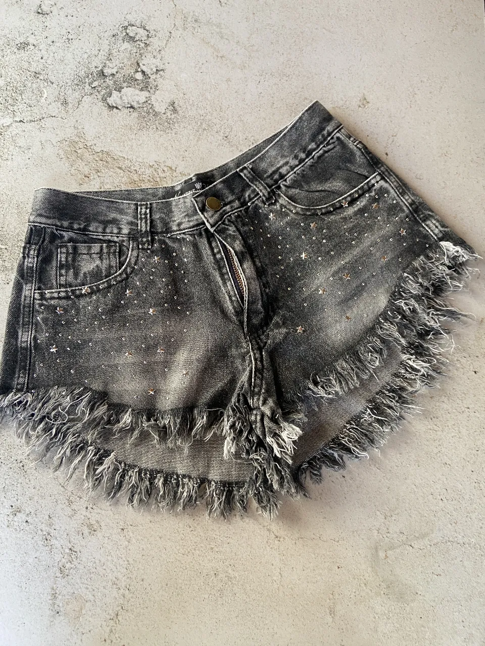 DISPONIBLE EN 36 y 38
Shorts de jean tiro alto con roturas y detalles de estrellas y brillos. Tienen flecos en el ruedo, dándole un toque canchero y moderno. Ideales para un look de día o noche.
