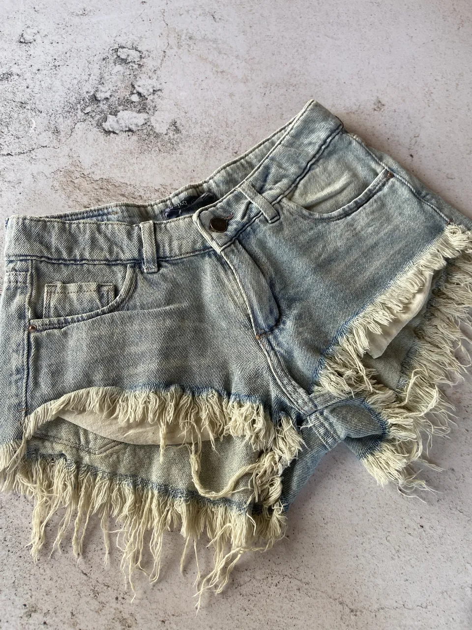 DISPONIBLE EN 34, 36 y 38
Shorts de jean tiro bajo con roturas y flecos. Un clásico para el verano, ideales para un look casual y descontracturado.