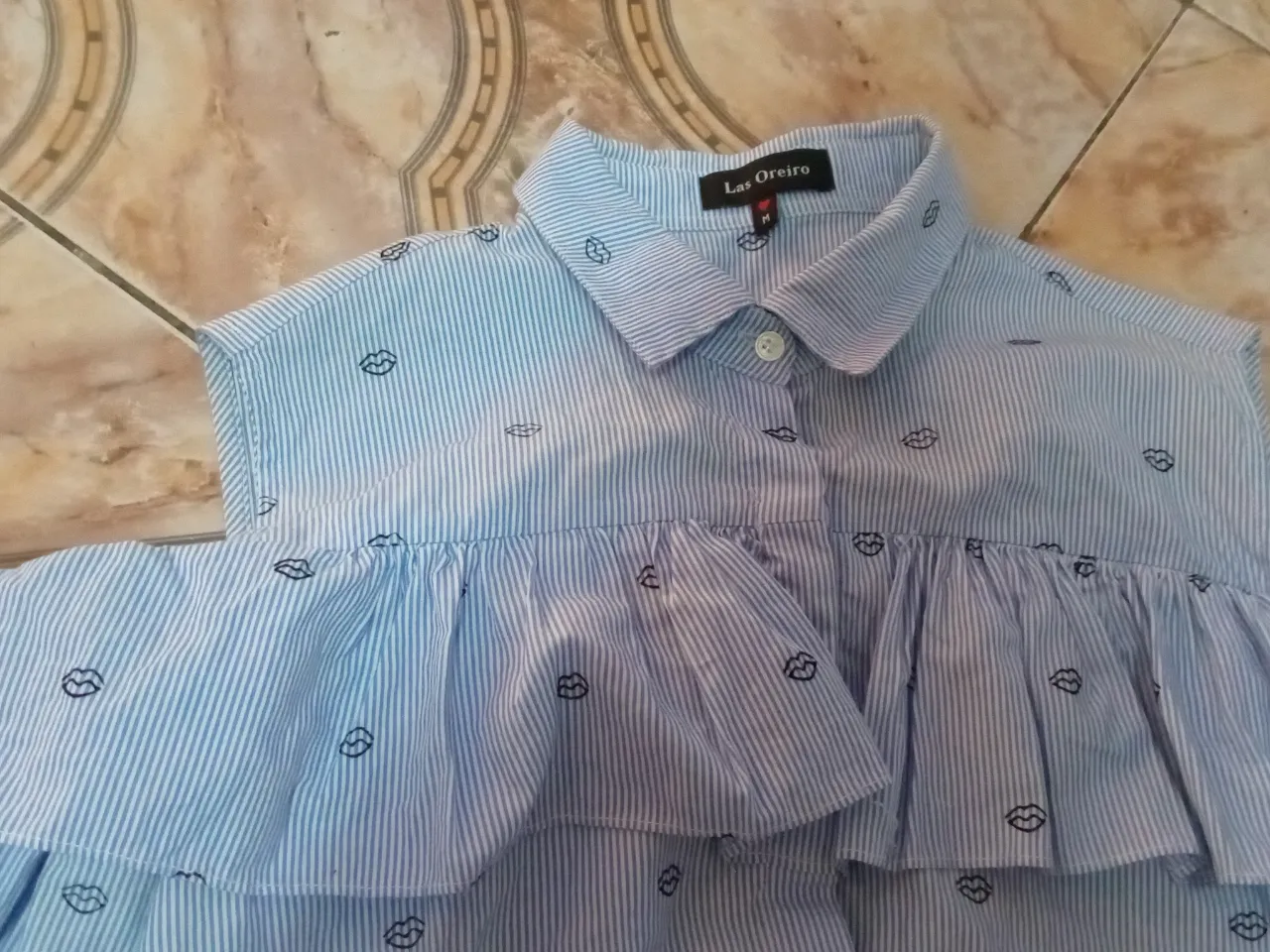 Blusa de mujer a rayas celeste y blanca con detalles de labios. Tiene volados y mangas largas. Marca Las Oreiro, talle M.