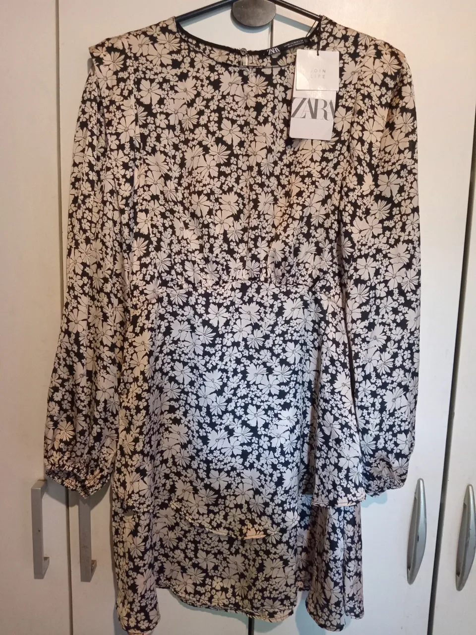 Vestido midi de Zara con estampado floral en blanco y negro. Tiene mangas largas con puños elastizados y un corte en la cintura. Cierre en la espalda.