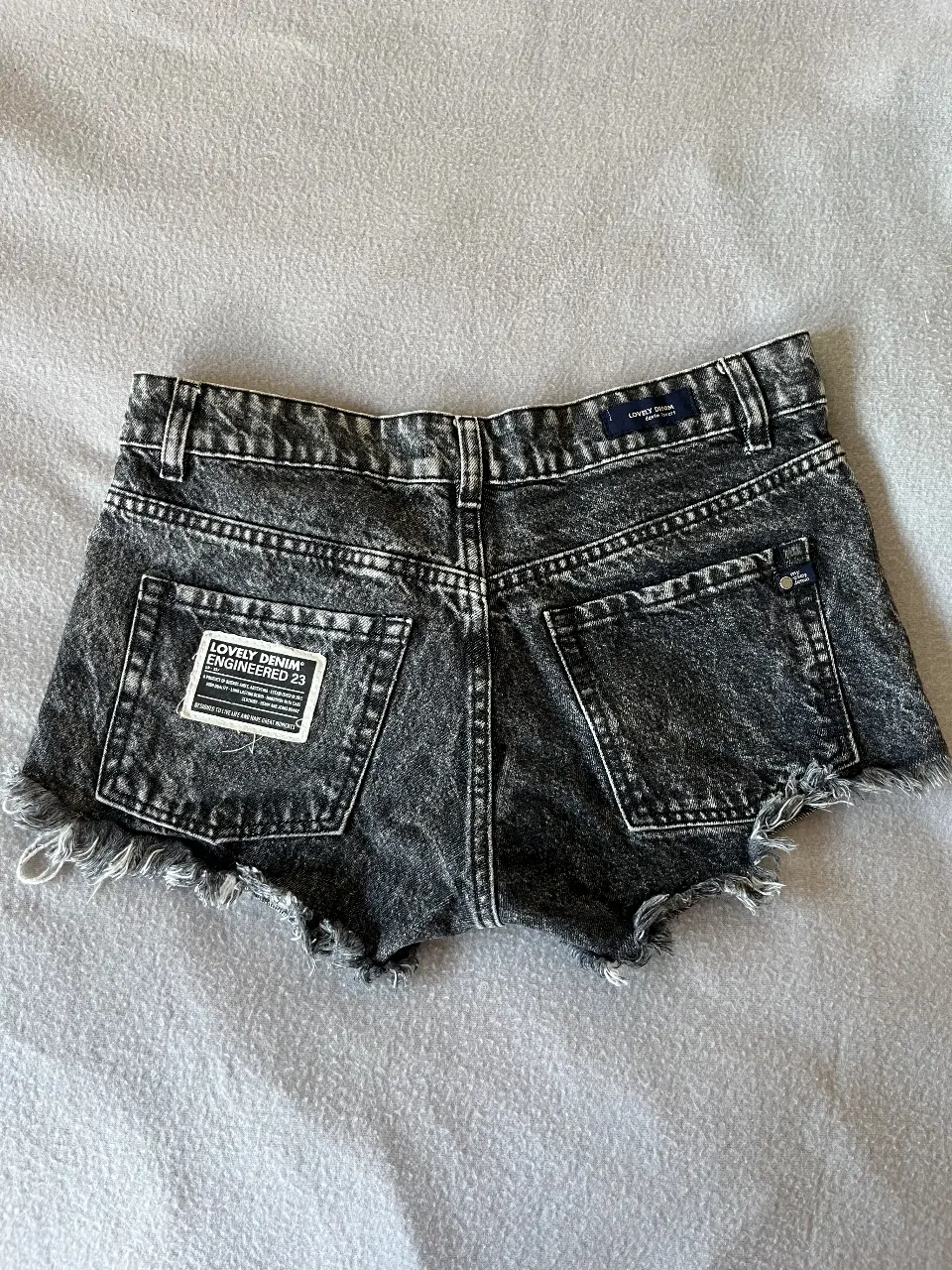 Short de jean negro gastado con detalles desflecados. Talle 26, tiro bajo. Ideal para un look casual y canchero.