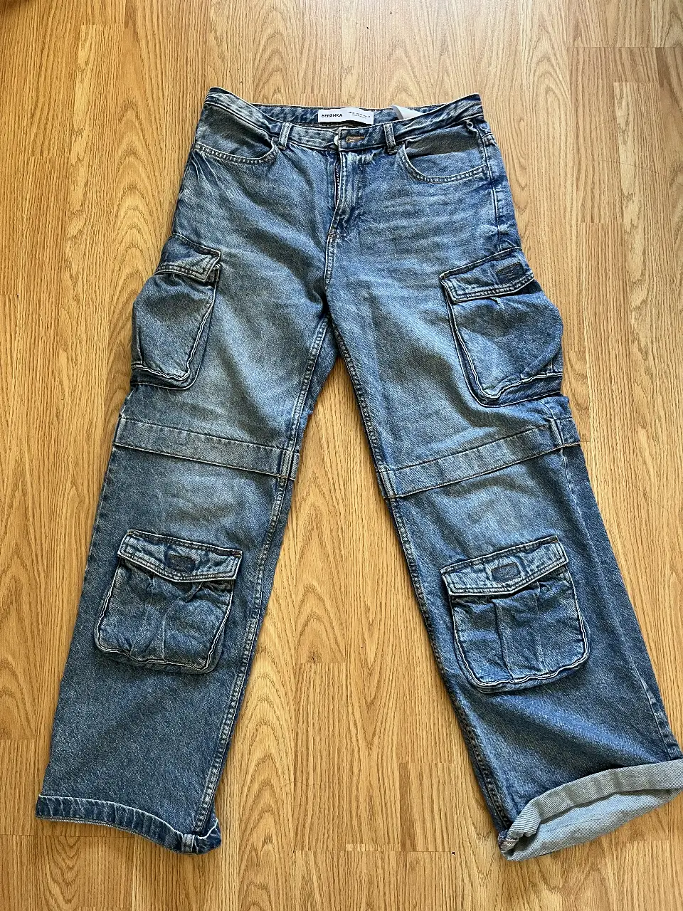 Jeans cargo, tiro bajo, con bolsillos amplios en las piernas y bolsillos traseros. Corte holgado y estilo utilitario.