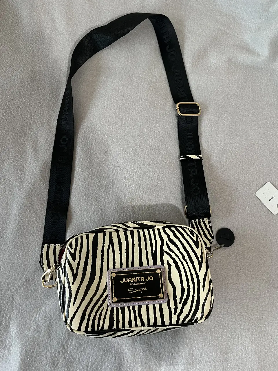 Bandolera con estampado de cebra, de la marca Juanita Jo. Ideal para un look canchero y moderno. Cuenta con correa ajustable y cierre.