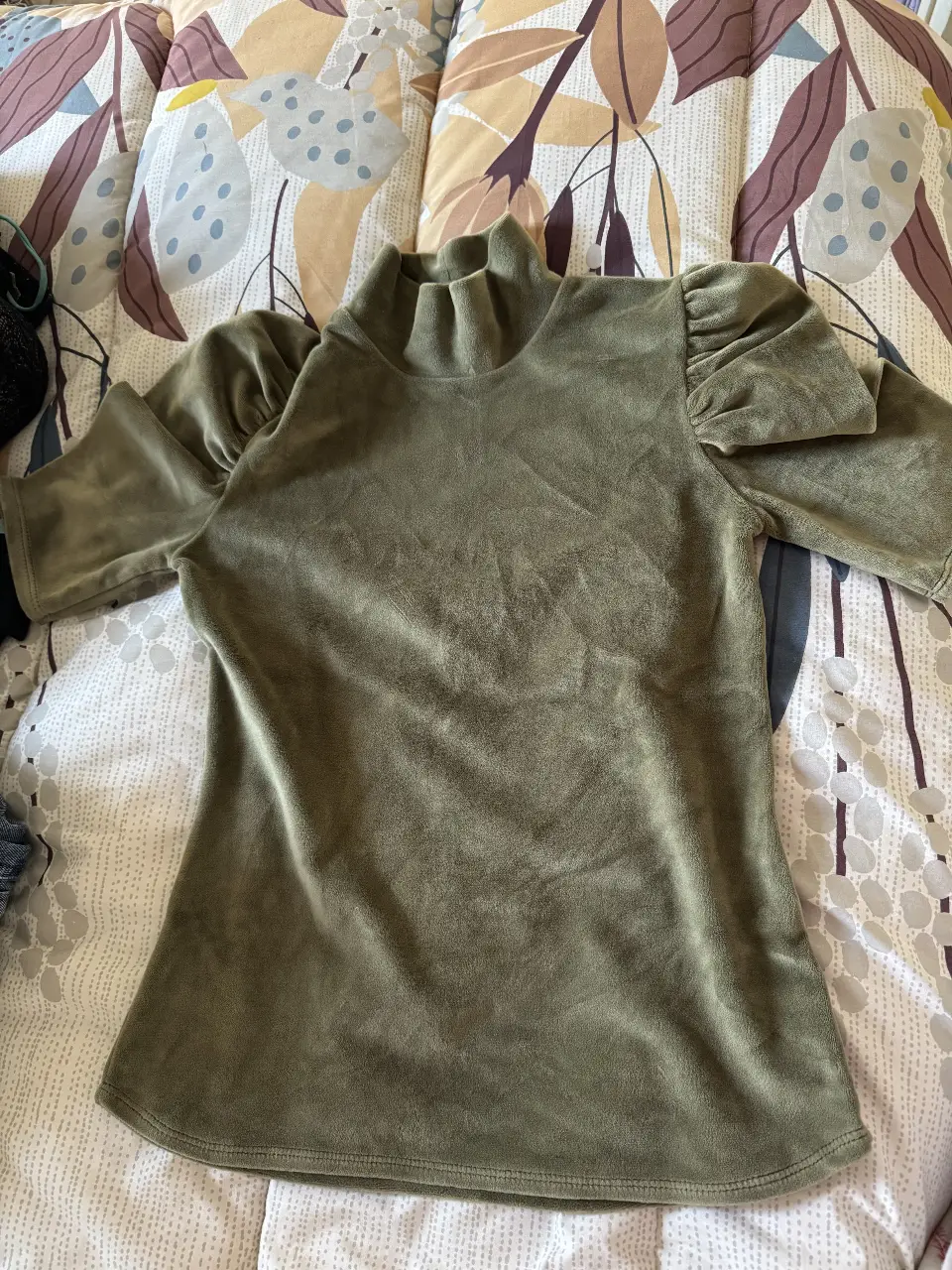 Blusa de terciopelo verde con cuello alto y mangas cortas abullonadas. Ideal para un look elegante y sofisticado.