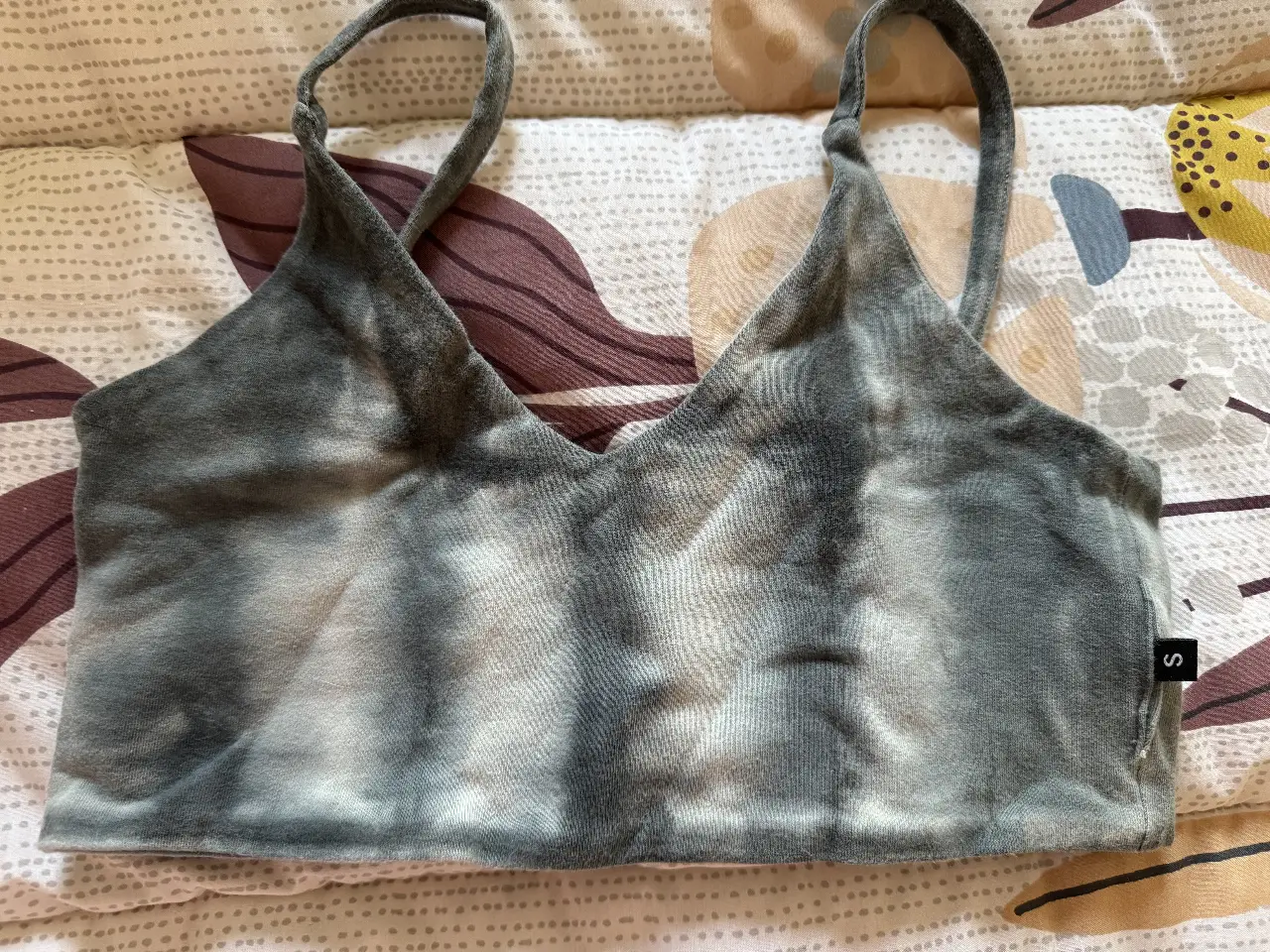 Top deportivo con diseño tie dye en tonos grises. Ideal para entrenamientos o looks casuales.