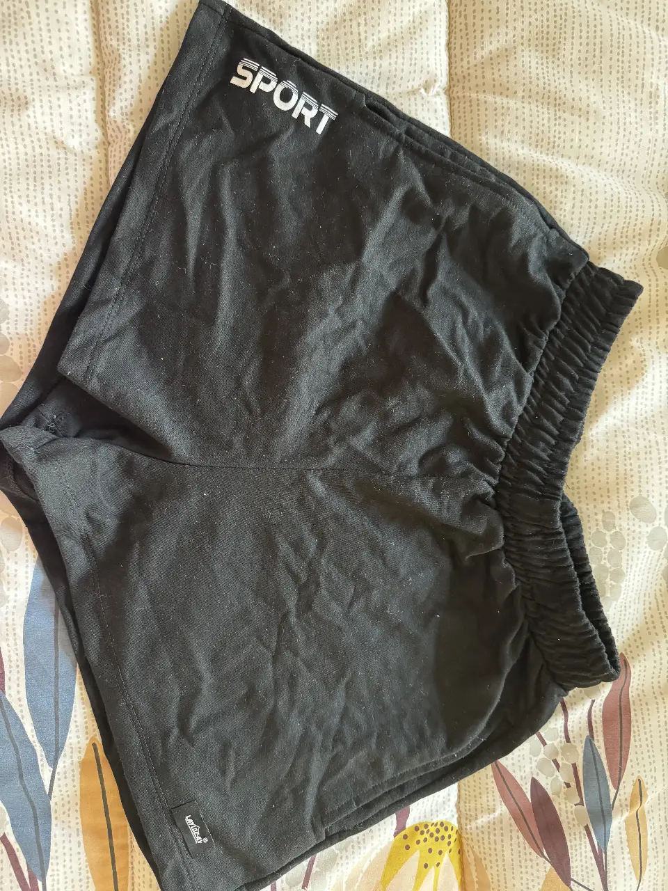 Short deportivo negro de tela suave, ideal para actividades físicas. Con cintura elastizada y detalle de la marca 'LAT LOLA'. Perfecto para un look cómodo y activo.