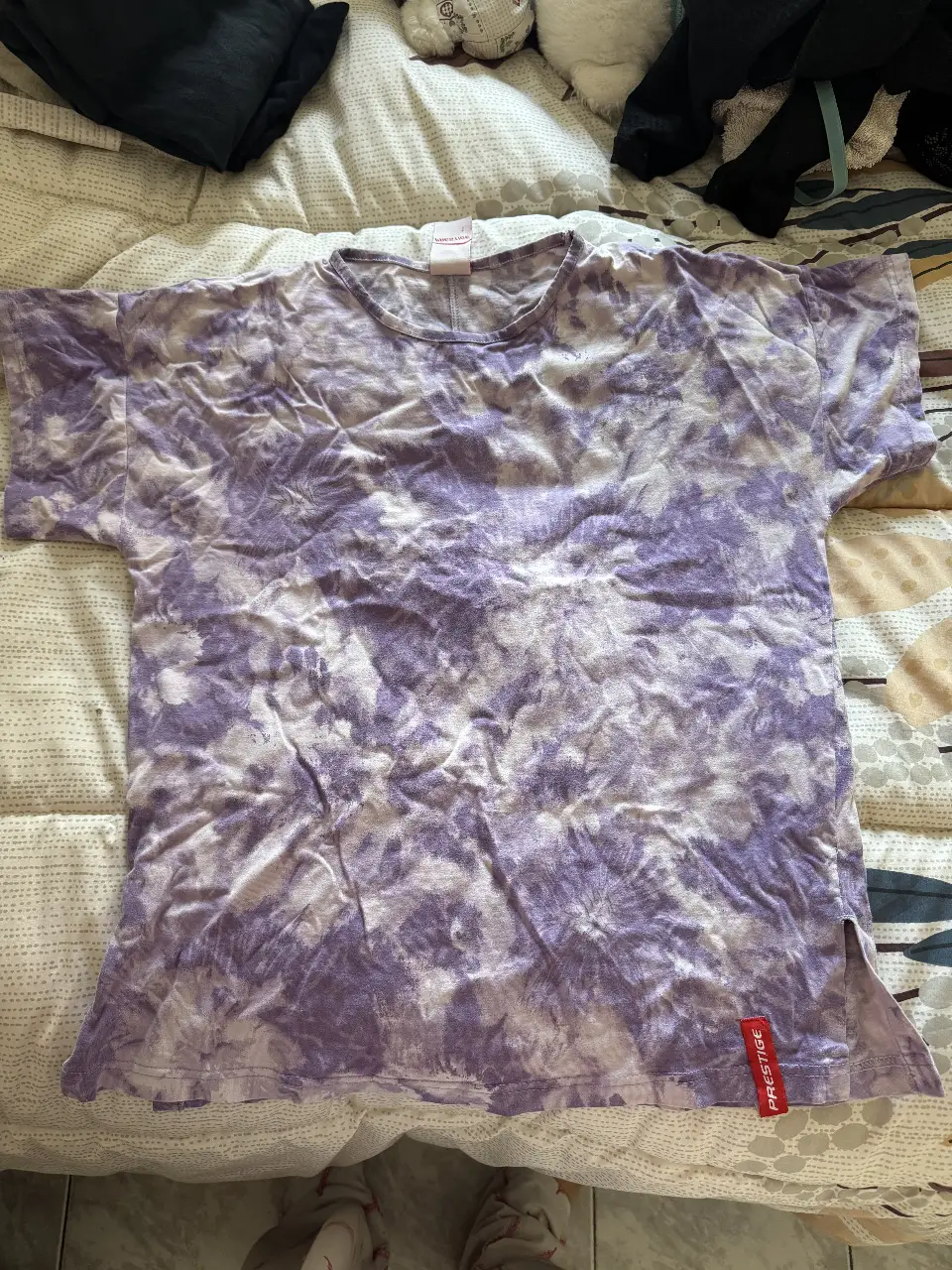Remera de mujer con estampado tie dye en tonos violetas y blancos. Cuello redondo y corte recto. Ideal para un look casual y cómodo.