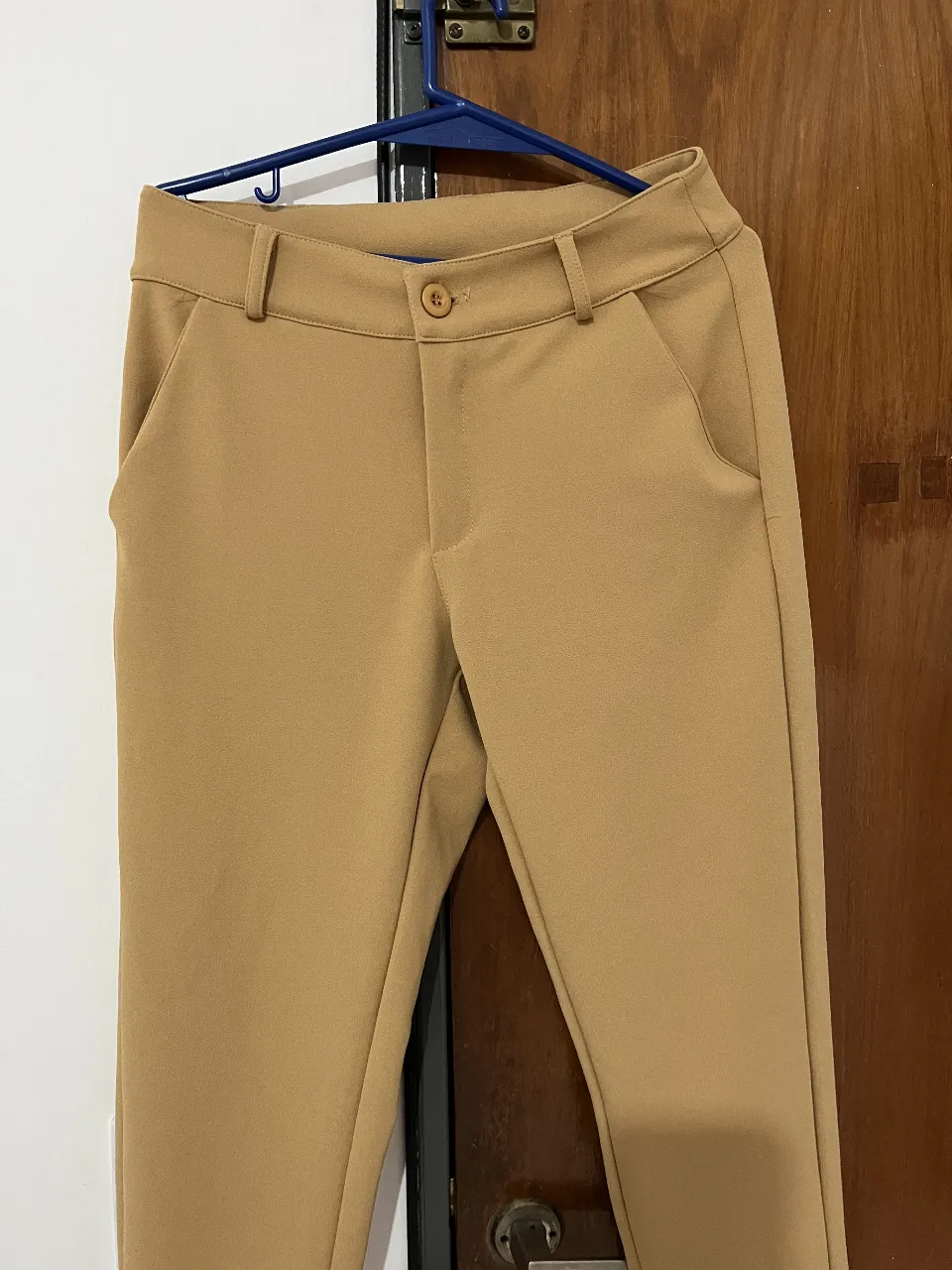 Pantalón sastrero color camel, tiro medio, con bolsillos delanteros y traseros. Ideal para un look elegante y versátil.