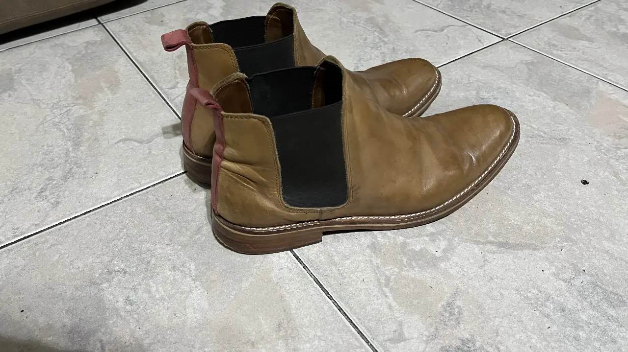Botines Chelsea de cuero marrón para hombre. Diseño clásico con elásticos laterales negros y detalles en rosa en la parte trasera. Ideales para un look casual y versátil.