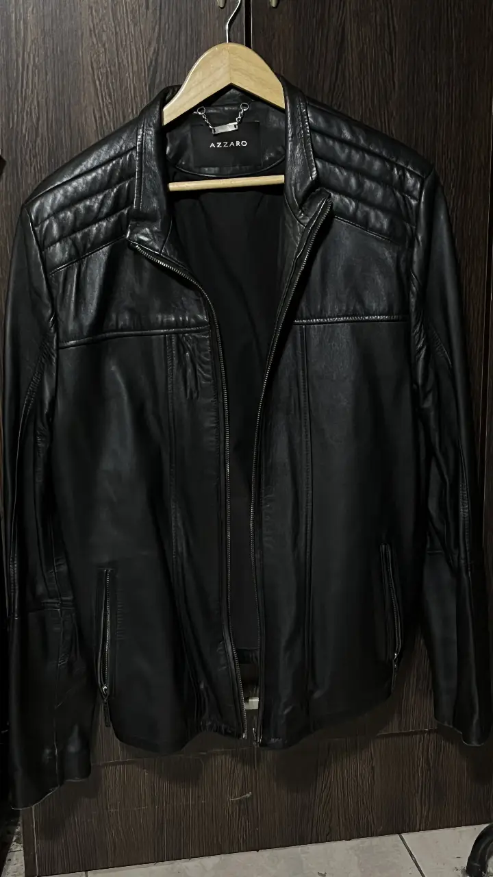 Chaqueta de cuero negro Azzaro para hombre. Diseño biker con detalles acolchados en los hombros y cierre. Ideal para un look moderno y audaz.