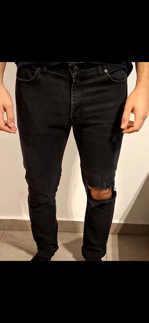 Jeans negro de hombre con roturas en la rodilla. Tiro medio, corte recto. Marca Levi's.