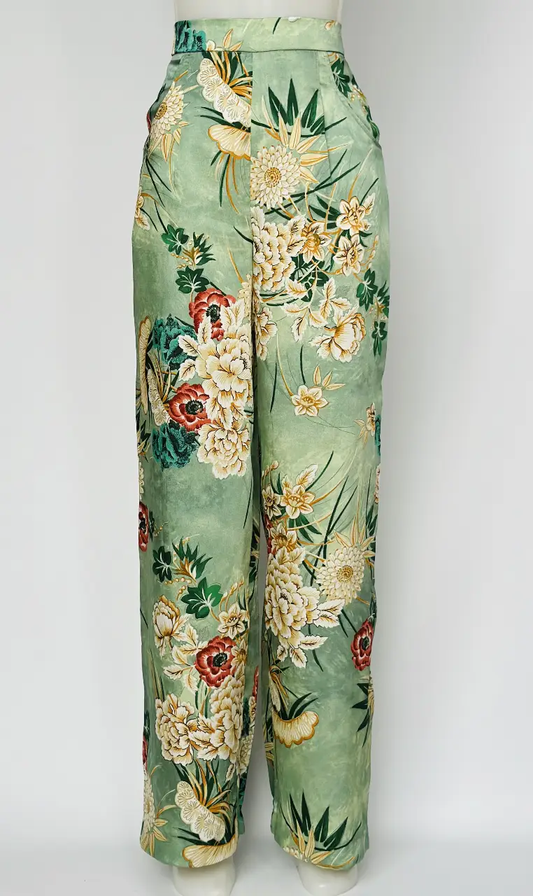 Pantalón sastrero de seda con estampado floral en tonos verdes, blancos y rojos. Tiro alto, corte recto y silueta fluida. Ideal para un look elegante y sofisticado.