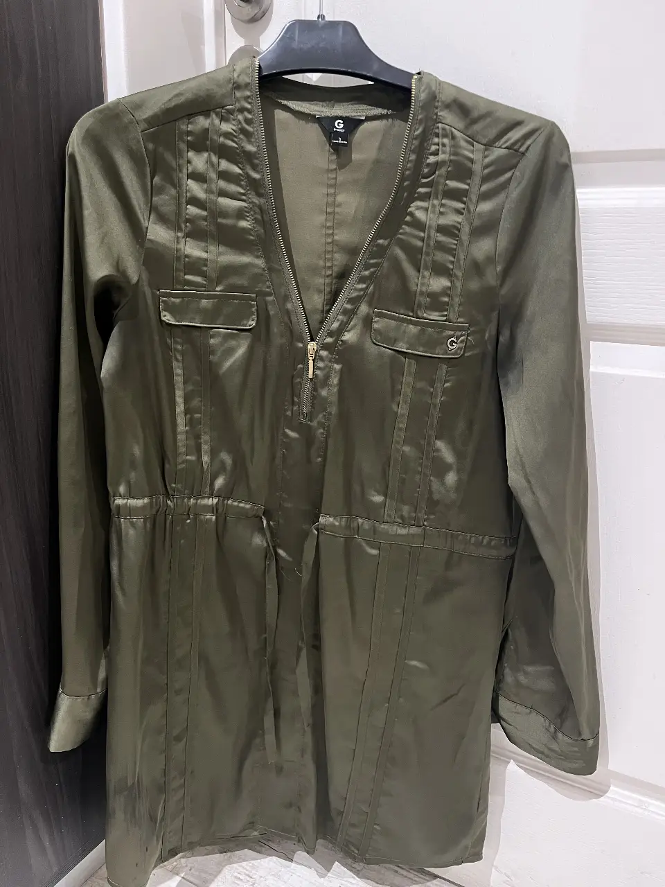 Blusa verde militar de la marca G by Guess, con cierre frontal y detalles de bolsillos. Talle S.