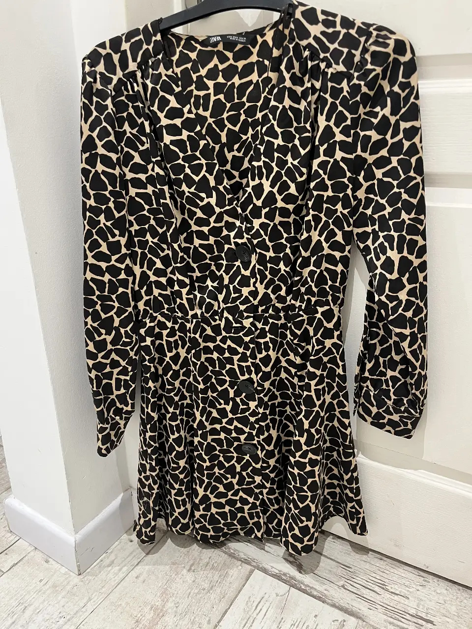 Vestido mini de Zara con estampado de manchas en marfil y marrón (jiraffe). Tiene mangas largas, botones en la parte delantera y un corte en la cintura que estiliza la figura. Ideal para una salida o evento casual.