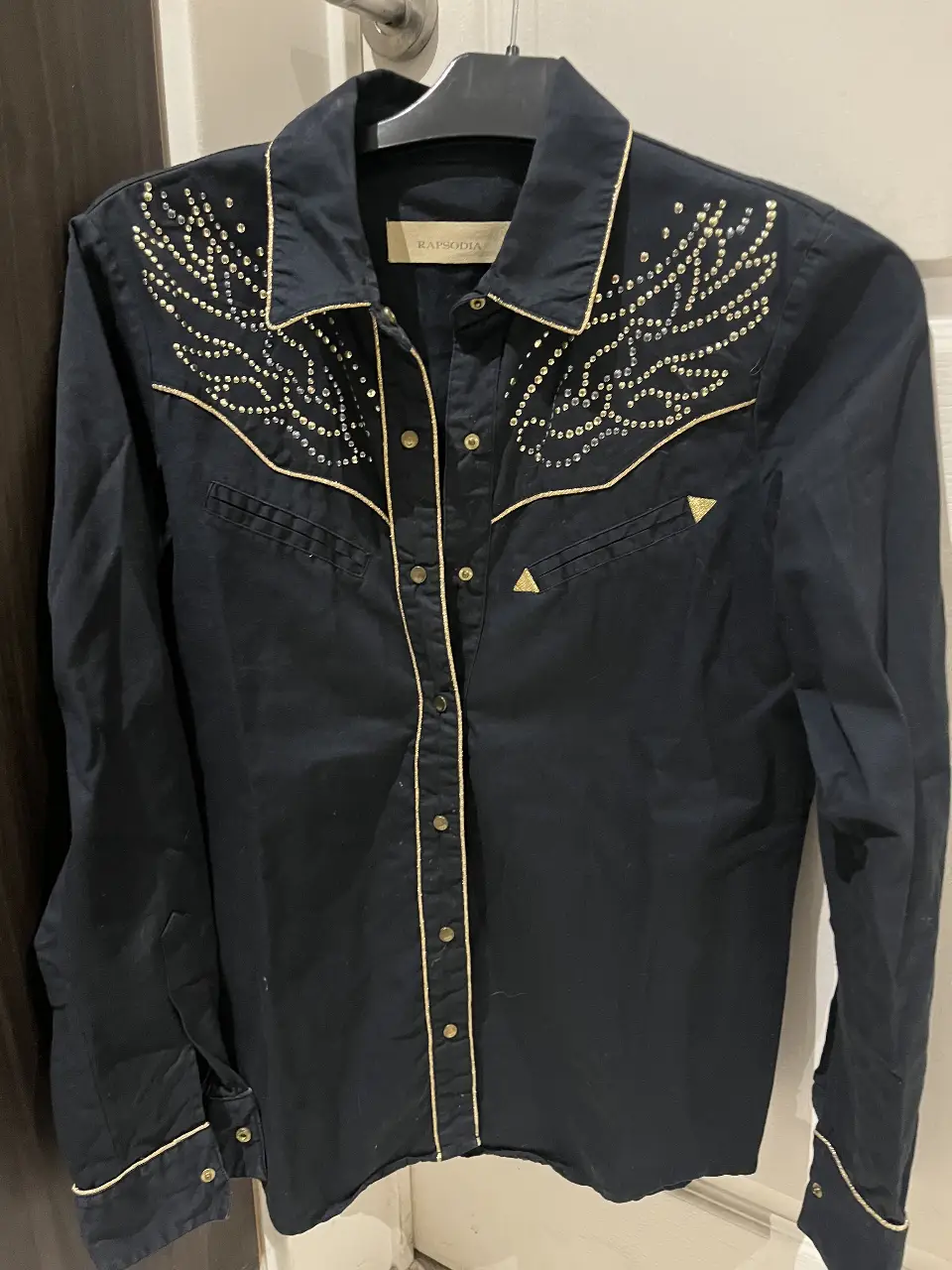 Camisa azul noche de mujer con detalles dorados y apliques. Estilo western, ideal para un look casual con un toque de originalidad.